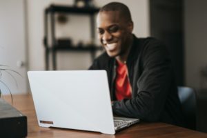 BIPOC male smiling at laptop